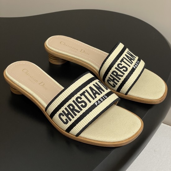 Angled pair of Dior natural and black raffia slides Angled pair view of Dior natural and black raffia slides on a dark surface