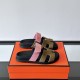 Hermes Chypre Suede Sandals Angled View on Orange Box in pink and olive Angled view of the Hermes Chypre suede sandals resting on an orange box in pink and olive