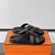 Hermes Kazimir Sandals angled view on box in black and green Angled view of the black and green sandals resting on an orange storage box