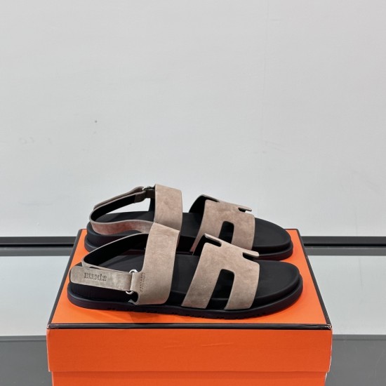 Hermes Genius Sandals In Etoupe Suede on Box in black Angled view of Hermes Genius Sandals In Etoupe Suede placed on an orange presentation box in black