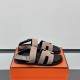 Hermes Genius Sandals In Etoupe Suede on Box in black Angled view of Hermes Genius Sandals In Etoupe Suede placed on an orange presentation box in black