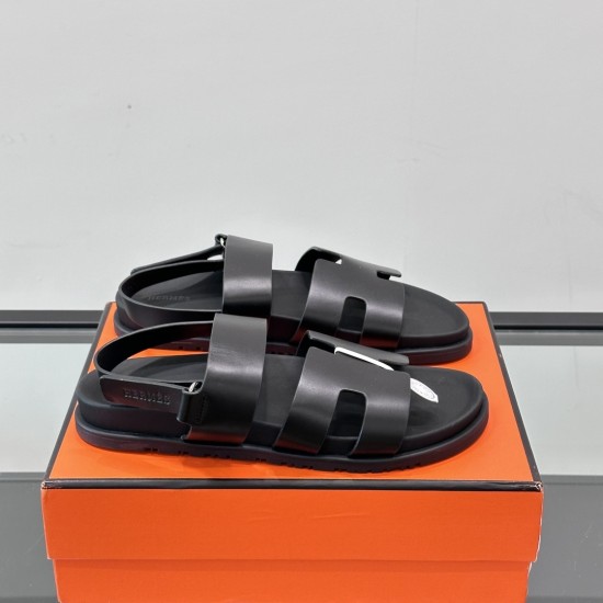Hermes Black Leather Sandals on Box Pair of black leather sandals resting on an orange storage box viewed from the side