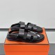 Hermes Black Leather Sandals on Box Pair of black leather sandals resting on an orange storage box viewed from the side