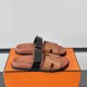 Hermes Brown And Black Sandals Angled View Hermes brown and black sandals angled view resting on signature orange box