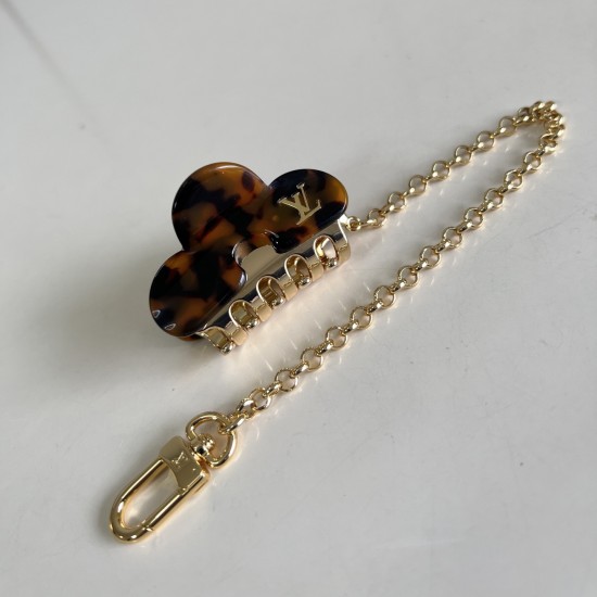 L Women's Dark Tortoise Hair Clip Bag Charm Angled View Angled top view of L Women's Dark Tortoise Hair Clip Bag Charm displaying logo detail and clasp
