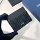 Men's Gloved hand holding men card holder at an angle against a light surface and packaging