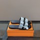 Angle view of Hermes Gabriel grey and black sandals resting on an orange box