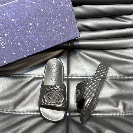 Gucci Black Rubber Slide Sandals Overhead Angle Top down perspective of one black rubber slide sandal beside a patterned storage box