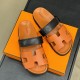 Hermes brown and black sandals top view on box Top-down view of Hermes brown sandals resting on an orange box displaying branding on the footbeds in brown and black