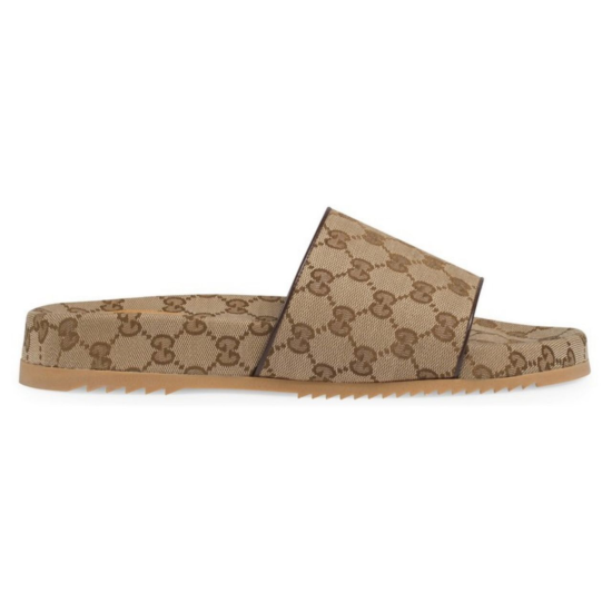 Side profile view of the beige and brown canvas slide sandal showing the flat sole and wide strap