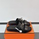 Hermes black sandals on orange box Angled view of Hermes black sandals resting on an orange brand box