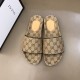 Top-down view of the pair of beige and brown monogram slide sandals next to a brand box