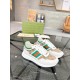 Three-quarter view of Gucci white leather and beige GG canvas trainers resting on glass table