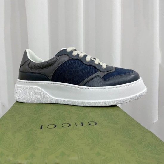 Side profile view of the Gucci chunky grey and blue lace-up trainer resting on a green shoe box