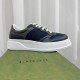 Side profile view of the Gucci chunky grey and blue lace-up trainer resting on a green shoe box