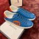 Blue Leather Trainers Side View in blue and orange Side profile of blue leather trainers with orange interlocking logo and white soles sitting on box