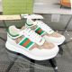 Gucci white leather and beige GG canvas trainers featuring green trim and side Web stripe displayed on a glass table