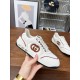 Hand holding Gucci white trainer highlighting side logo patch and sole branding in white and brown