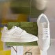 Gucci White Leather Trainers Display View in white and gold Gucci white leather trainers resting against green patterned shoe box in white and gold