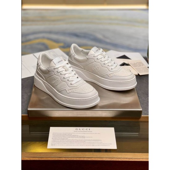 Pair of Gucci white embossed leather trainers resting on display table