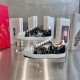 Christian Louboutin Low Top Trainers Display View in black and white Two Christian Louboutin low top spiked trainers arranged on a glass stand in black and white
