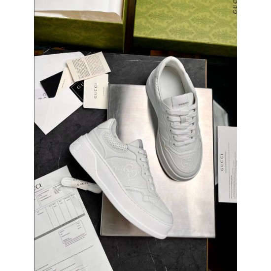 Overhead layout of Gucci white leather trainers beside original packaging documentation
