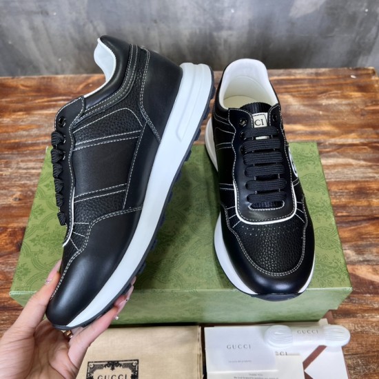 Pair of Gucci black leather trainers resting on green shoe box in black and white