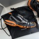 Side angle view of black and orange Balenciaga 3XL trainer resting on a branded dust bag