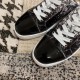 Close-up of the glossy black patent toe cap on Christian Louboutin trainers in black and white