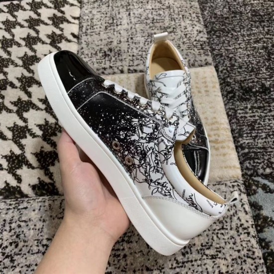 Handheld view showing medial side ventilation eyelets and script pattern on Christian Louboutin trainers in black and white