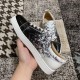 Handheld view showing medial side ventilation eyelets and script pattern on Christian Louboutin trainers in black and white