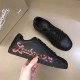 Christian Louboutin Black Trainer Side Profile in black and red Hand holding Christian Louboutin black low top trainer showing red side script