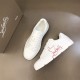 Angled top-down layout of Christian Louboutin white trainers on neutral background in white and red