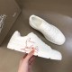 Hand holding Christian Louboutin white trainer showing red script print along side panel
