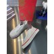 Side elevation of Christian Louboutin white low top trainer on reflective surface in white and red
