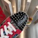 Close-up of the black patent toe cap adorned with silver metallic spikes on Christian Louboutin trainers in multicolour and red