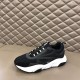 Dior B22 Black Trainer Three-Quarter View in black and white Three-quarter lateral view of the Dior B22 black trainer resting on a padded seat in black and white