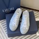 Top-down pair view of Dior B23 low-top trainers resting on a navy presentation box in grey and white