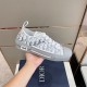 Handheld lateral view of white and grey Dior B23 low-top trainer demonstrating overall silhouette