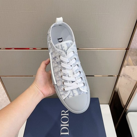 Single shoe overhead perspective of grey and white Dior B23 low-top trainer held over box
