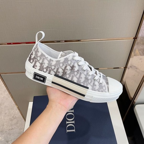 Hand holding single grey Dior B23 trainer highlighting side design details in grey and white