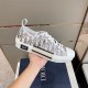Hand holding single grey Dior B23 trainer highlighting side design details in grey and white