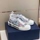 Side angled view of Dior B23 low-top floral print trainers resting on shoe box in blue and pink