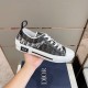 Dior B23 Low Top Black Monogram Canvas Trainer Handheld View in black and white Hand holding Dior B23 Low Top Black Monogram Canvas Trainer showing side details in black and white