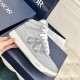Dior B27 High-Top Grey Canvas Trainer - Handheld Side View in grey and white Handheld lateral view of Dior B27 high-top grey trainer showcasing leather panelling and stitching in grey and white