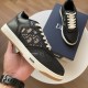 Hand holding a black Dior B27 trainer displaying side monogram canvas panel and white sole