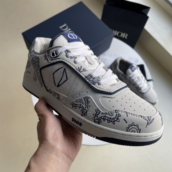 Hand holding Dior white and navy paisley print low-top trainer