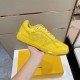 Hand holding yellow Dior B27 trainer showing lateral side branding