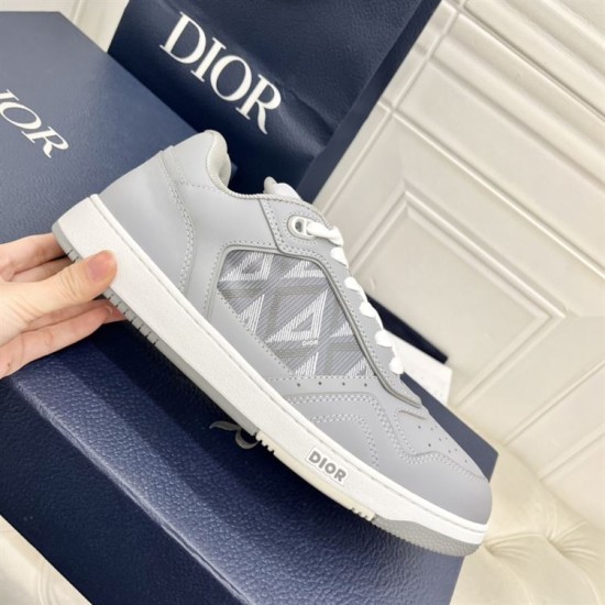 Side view of the Dior B27 grey trainer held up against blue shoe packaging in grey and white