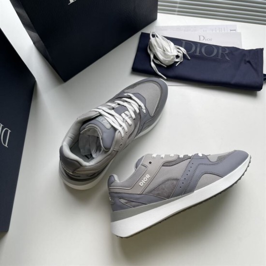 Top-down view of a pair of Dior grey trainers resting on a surface next to packaging in grey and white